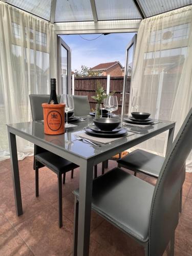 a dining table with a bottle of wine on it at CONTRACTORS OR FAMILY HOUSE - M1 Nottingham - IKEA RETAIL PARK - CATKIN DRIVE - 2 Bed Home with Driveway, private garden, sleeps 4 - TV'S in all rooms in Giltbrook