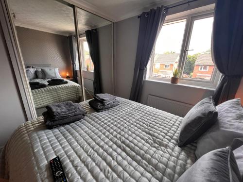 1 dormitorio con 2 camas y un espejo grande en CONTRACTORS OR FAMILY HOUSE - M1 Nottingham - IKEA RETAIL PARK - CATKIN DRIVE - 2 Bed Home with Driveway, private garden, sleeps 4 - TV'S in all rooms 