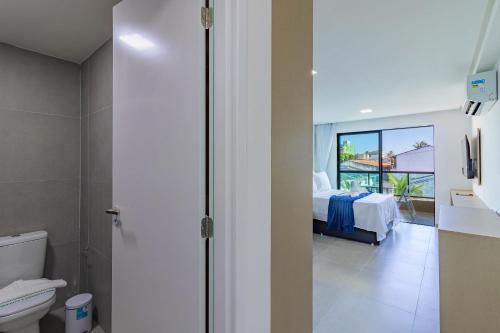 un bagno con servizi igienici e una camera con letto di Villa Del Mar #101 - Suíte em Porto por Carpediem a Porto De Galinhas