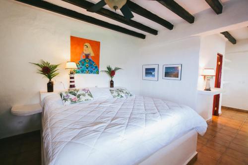 a bedroom with a white bed with a painting on the wall at OceanFront Bungalows - Paradise Rentals in Santa Catalina