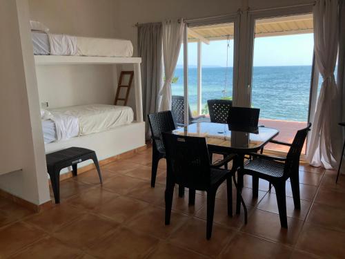 a dining room with a table and chairs and a bedroom at OceanFront Bungalows - Paradise Rentals in Santa Catalina