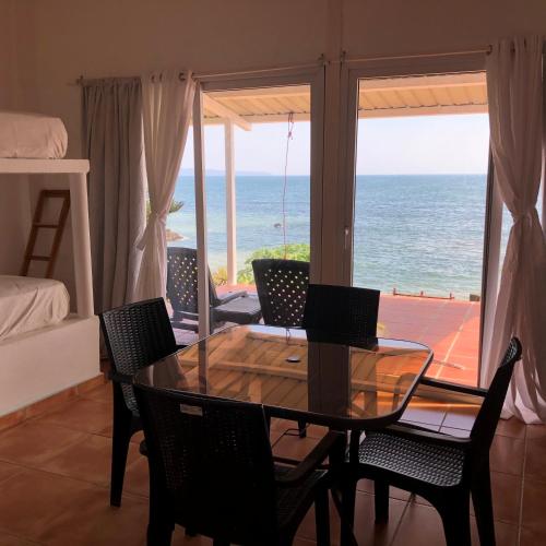 a dining room with a table and chairs and the ocean at OceanFront Bungalows - Paradise Rentals in Santa Catalina