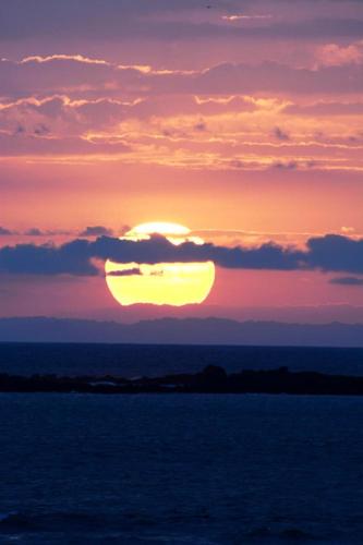 a sunset over the ocean with the sun setting at OceanFront Bungalows - Paradise Rentals in Santa Catalina