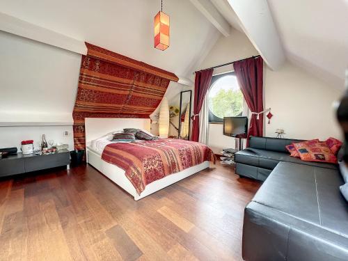 a bedroom with a bed and a couch at Suite de luxe avec espace salon et balnéo à la campagne in Opprebais