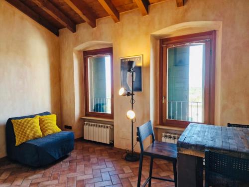 ein Wohnzimmer mit einem Sofa, einem Tisch und Fenstern in der Unterkunft Vittoria alla Torre in Pozzolengo