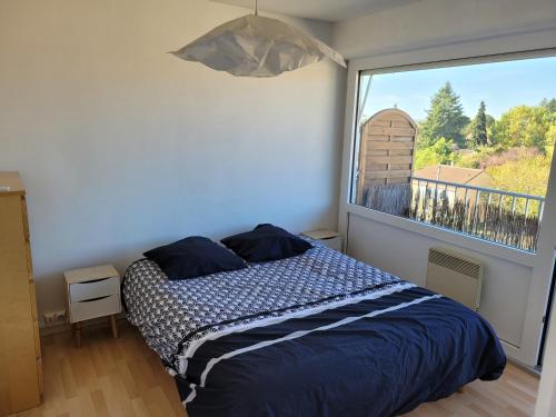 een slaapkamer met een bed en een groot raam bij Appartement centre-ville de Bergerac 4 personnes in Bergerac