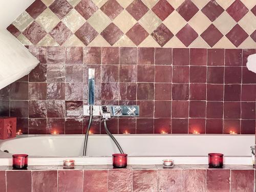 a bathroom with a bath tub with red candles at Suite de luxe avec espace salon et balnéo à la campagne in Opprebais