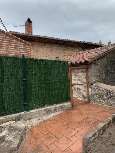 a building with a green fence and a brick patio at La Breval in Alles