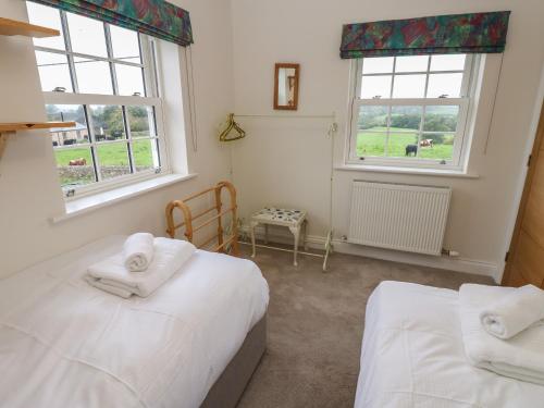 a bedroom with two beds and two windows at Larch House in Penrith