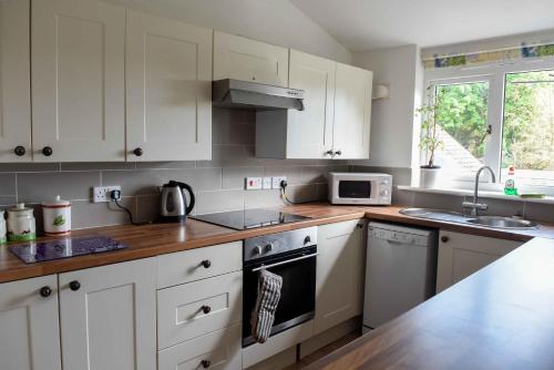 cocina con armarios blancos y fogones en Bench Tor Apartment, en Plymouth