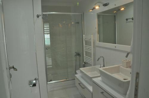 a white bathroom with two sinks and a shower at Trabzon Panoramic View Vip Apart in Trabzon