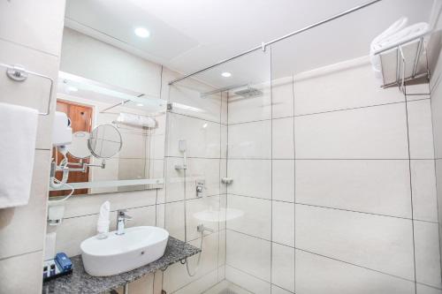 Baño blanco con lavabo y espejo en KKM INTERNATIONAL, en Trivandrum