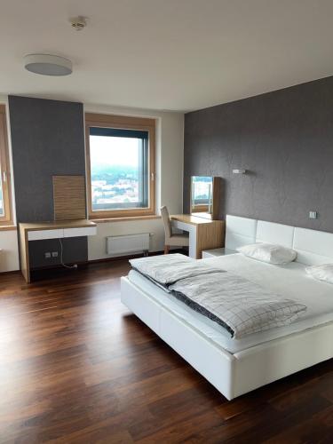 AZ Tower Apartment في برنو: غرفة نوم مع سرير أبيض كبير ومكتب