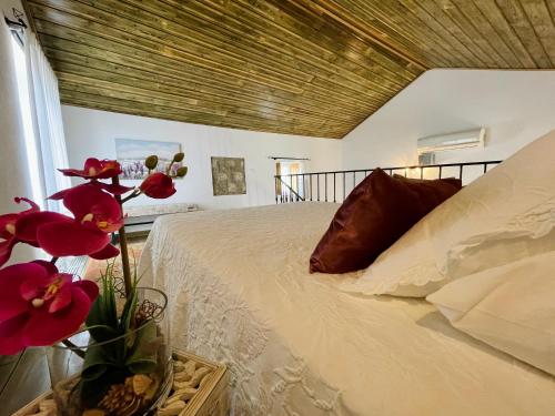 a bedroom with a bed and a vase with flowers at Tufa Guest House, Wellness & SPA - Villa Campus in Corredoura