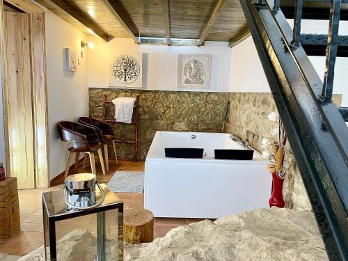 a white bath tub in a room with a table at Tufa Guest House, Wellness & SPA - Villa Campus in Corredoura