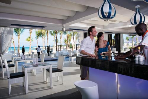 un hombre y una mujer parados en un bar en una playa en Riu Palace Jamaica - Adults Only - All Inclusive Elite Club en Montego Bay