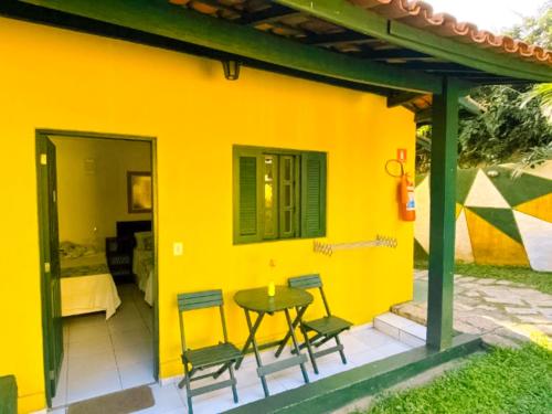 une maison jaune avec une table et des chaises sur une terrasse dans l'établissement VELINN Pousada Aporan Ilhabela, à Ilhabela