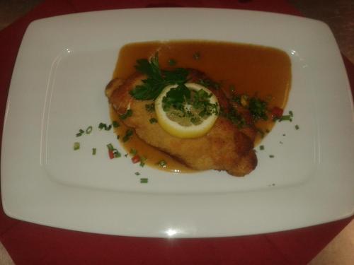 a white plate with a piece of fish with a lemon on it at Hotel Restaurant Albans Sonne in Bad Rippoldsau