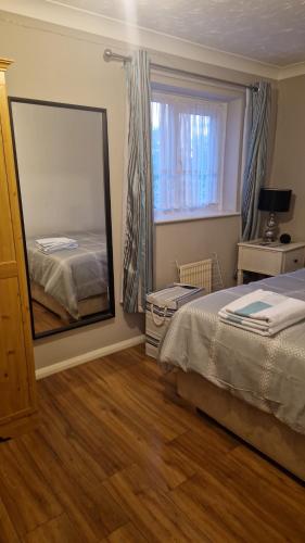 sypialnia z lustrem, łóżkiem i oknem w obiekcie Yvonnehut w Luton