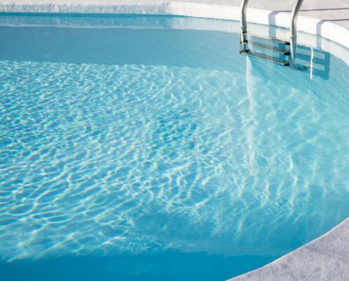 a pool of blue water with a ladder in it at Bungalows Las Almenas in Maspalomas