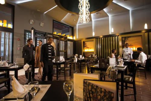 a man standing in a restaurant with tables and chairs at Riu Palace Jamaica - Adults Only - All Inclusive in Montego Bay