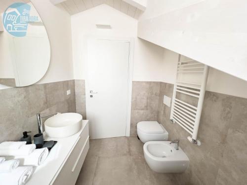 La salle de bains blanche est pourvue d'un lavabo et de toilettes. dans l'établissement Tarabochia 8 Tirabora Short Rent, à Trieste