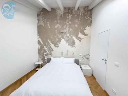 1 dormitorio con cama blanca y pared en Tarabochia 8 Tirabora Short Rent, en Trieste