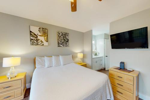 a bedroom with a white bed and a flat screen tv at Beachwalk Condominiums 6F in Panama City Beach