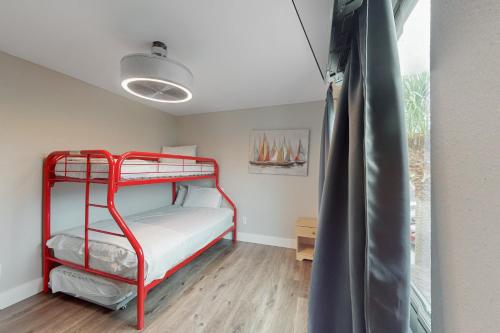 a red bunk bed in a room with a window at Beachwalk Condominiums 6F in Panama City Beach