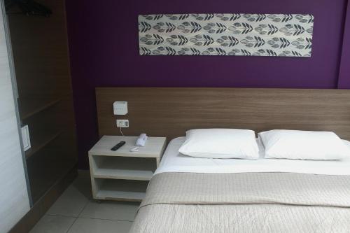 a bedroom with a bed and a purple wall at Imperial Flat Tambaú 311 in João Pessoa