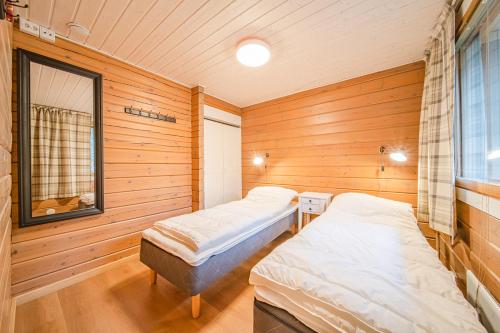 two beds in a room with wooden walls and a window at Levillas Lammaskuru in Levi