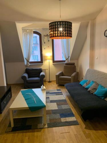 ein Wohnzimmer mit einem Sofa und einem Tisch in der Unterkunft Spacious 2-rooms penthouse in Warsaw city center in Warschau