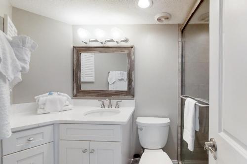 Baño blanco con lavabo y espejo en Plantation West Resort III, en Gulf Shores