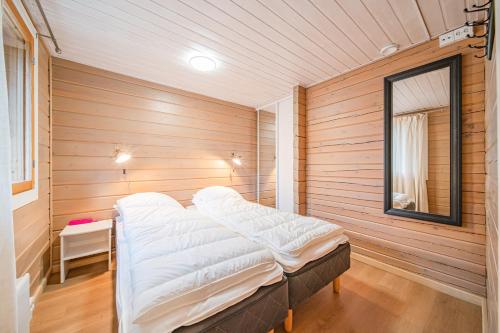 a bedroom with a bed in a room with wooden walls at Levillas Lammaskuru A in Levi