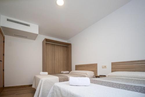 a room with three beds with white linens at Apartamentos 7 Puentes Sierra Cazorla Las 5 casas iguales in Burunchel
