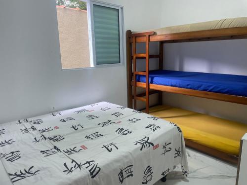 1 dormitorio con 2 literas con sábanas azules en Casa novinha - Praia Grande - Mirim - 3 quadras da Praia Wi-Fi en Praia Grande