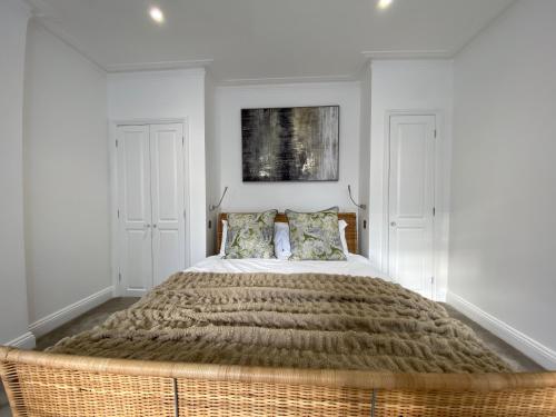 a bedroom with a large bed with a wicker headboard at Stylish Traveller's Heaven in London