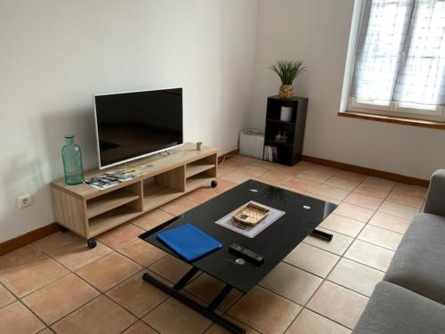 a living room with a flat screen tv and a coffee table at Appartement avec terrasse in Gien