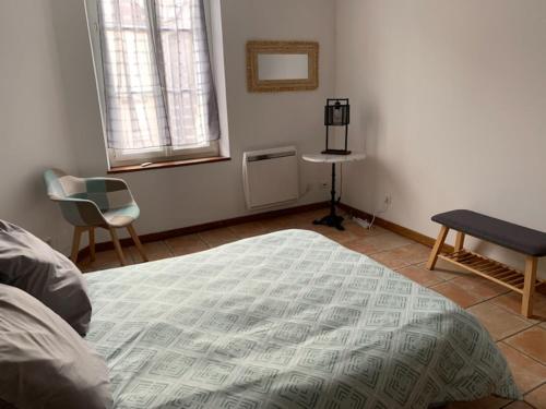 a bedroom with a bed and a table and a chair at Appartement avec terrasse in Gien