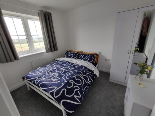 een slaapkamer met een bed met een blauw en wit dekbed bij Homeaway in Wellingborough