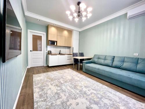 a living room with a blue couch and a kitchen at Элитная квартира возле площади in Shymkent