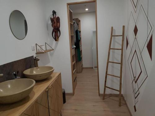 uma casa de banho com dois lavatórios num balcão e uma escada em gîte la vie en couleur 14 personnes em Saint-Paul-en-Gâtine
