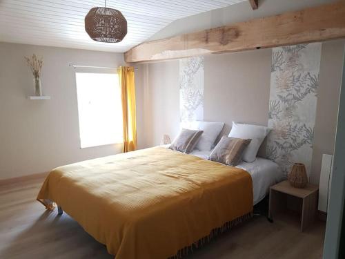 um quarto com uma cama grande e um cobertor amarelo em gîte la vie en couleur 14 personnes em Saint-Paul-en-Gâtine