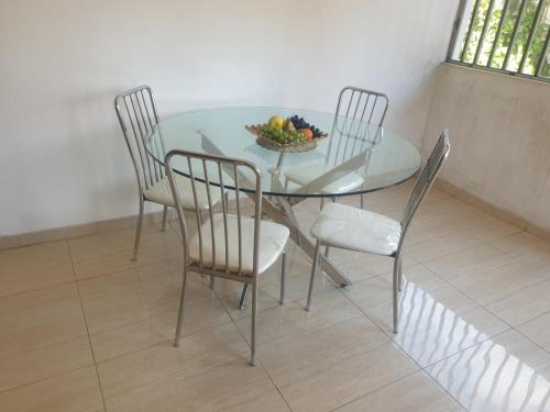 a glass table with chairs and a bowl of fruit on it at Bianca's in Matola