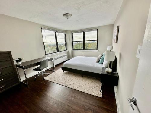 Schlafzimmer mit einem Bett, einem Schreibtisch und Fenstern in der Unterkunft Gorgeous Furnished Apt 2br Free Parking, Gym, Ave in Philadelphia