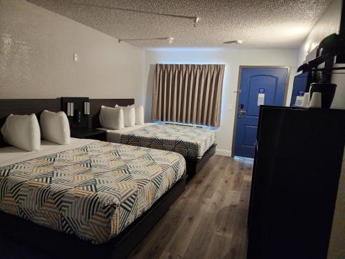 Motel 6 Sacramento CA Natomas في سكرامنتو: غرفه فندقيه سريرين وباب ازرق