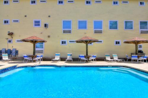 a swimming pool with chairs and umbrellas in front of a building at Beachgate Condo Suites and Hotel 512a condo in Port Aransas