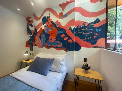a bedroom with a bed and a painting on the wall at Supertramp Hostel Machupicchu in Machu Picchu