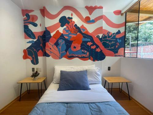 a bedroom with a bed with a painting on the wall at Supertramp Hostel Machupicchu in Machu Picchu