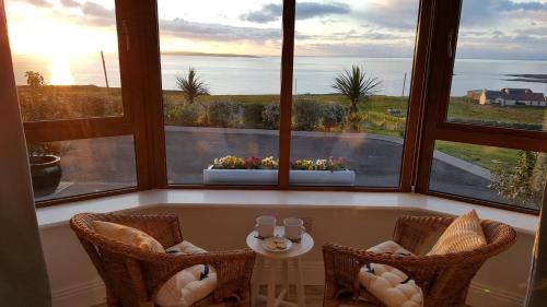 a room with three windows with a view of the ocean at Blue Ocean Guest Suites in Doolin